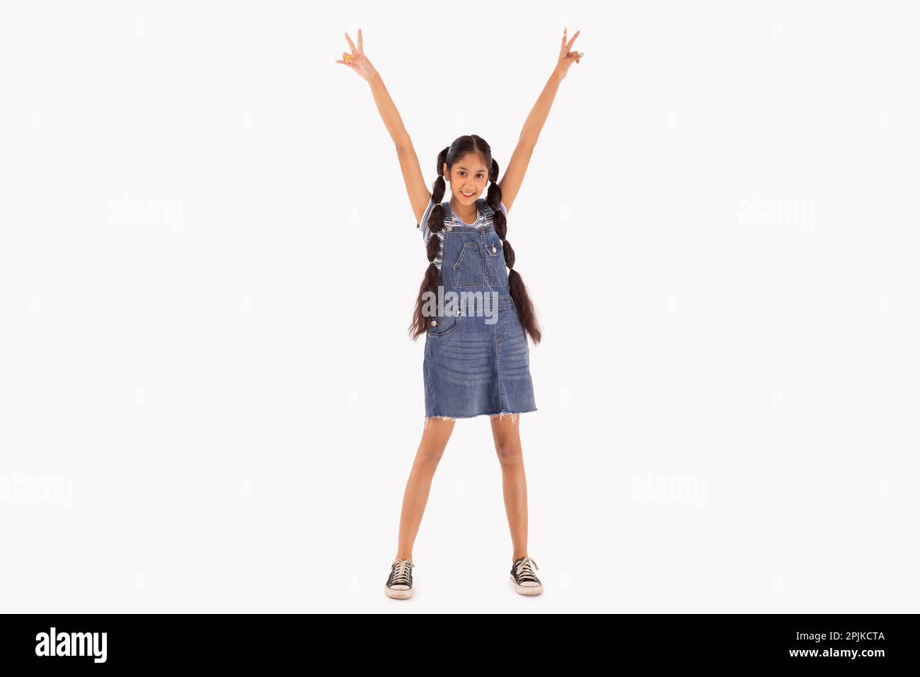 Tween girl with braided hair gesturing with hands up against white background Stock Photo