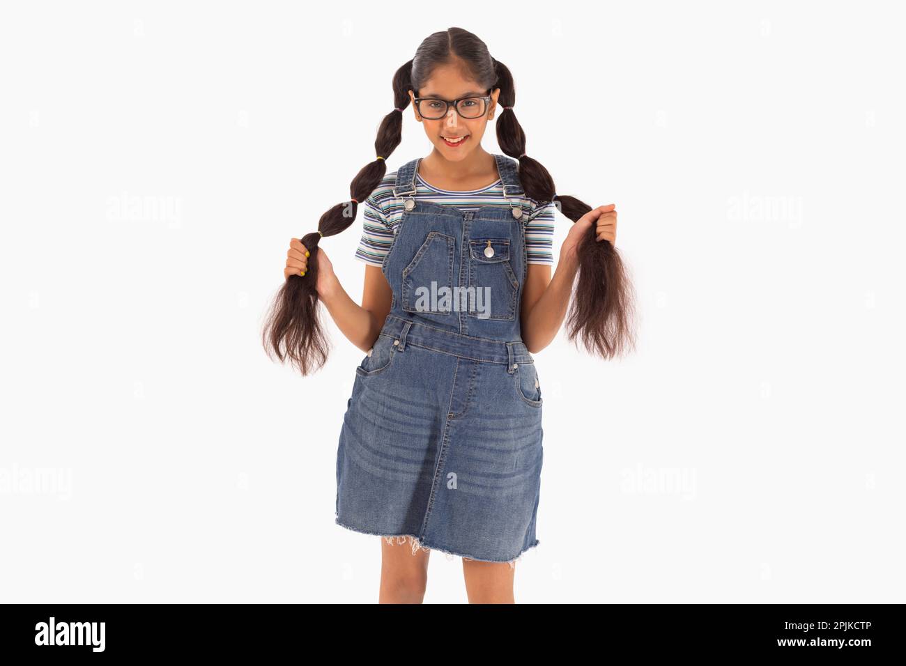 Tween girl with spectacles holding her braided hair against white background Stock Photo