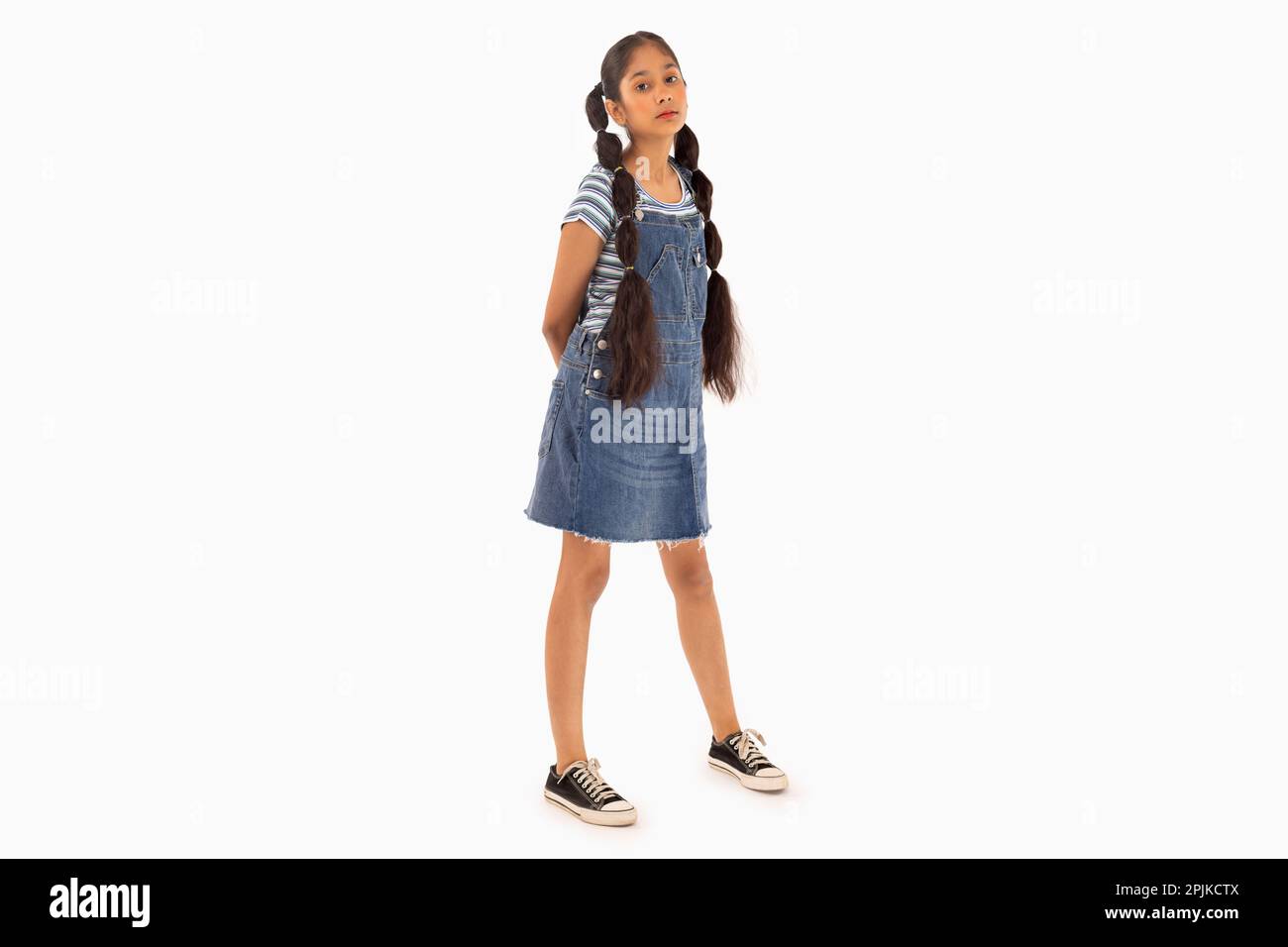 Tween girl with braided hair standing against white background Stock Photo