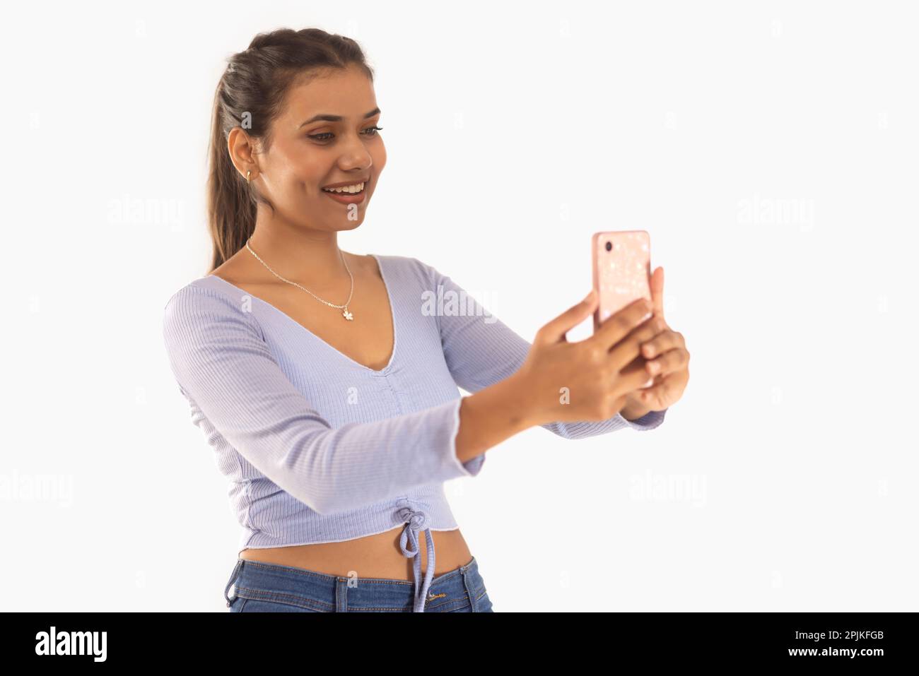 Portrait of a cheerful woman taking selfie against white background ...