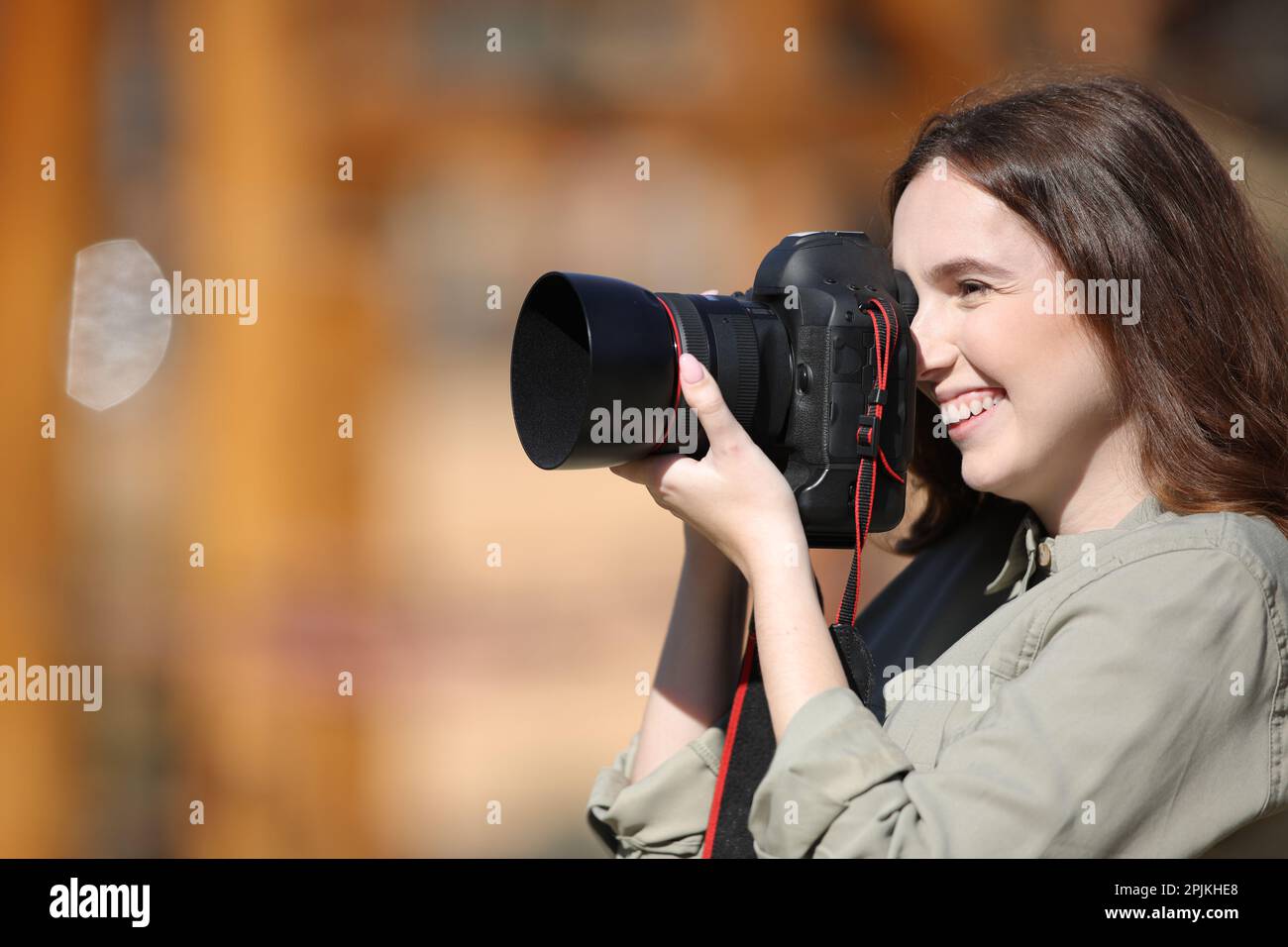 Side view portrait of a happy photographer taking photos outdoor Stock Photo