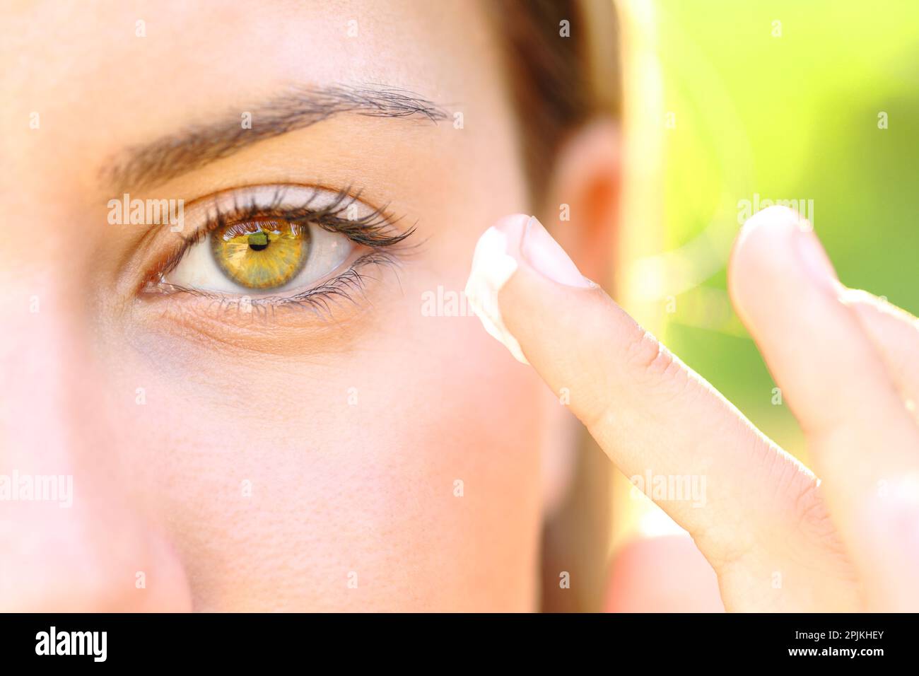Close up of a woman hand hydrating face near the eye with moisturizer outdoor Stock Photo