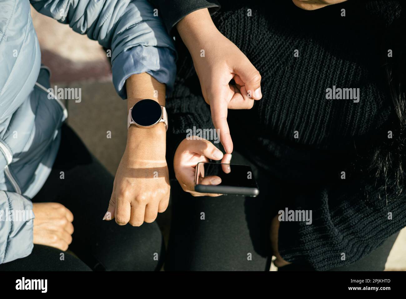 three Latin people using their mobile devices and interacting with each other Stock Photo