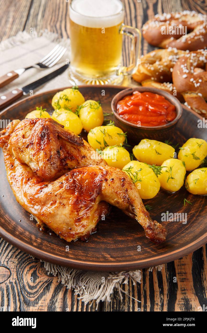 German holiday food half fried chicken with boiled potatoes, sauce, beer and pretzels close-up on a wooden table. Vertical Stock Photo