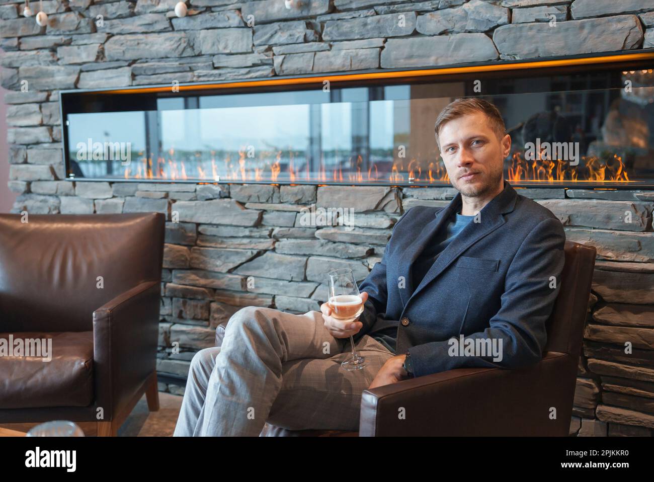 Man with wineglass sitting in chair at luxury hotel during vacation Stock Photo