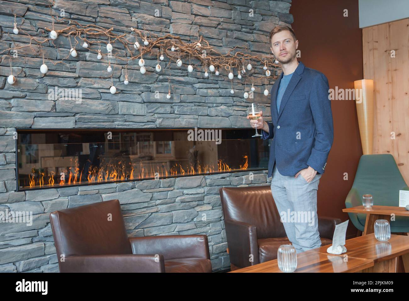 Man with wineglass standing by chair at luxury hotel during vacation Stock Photo