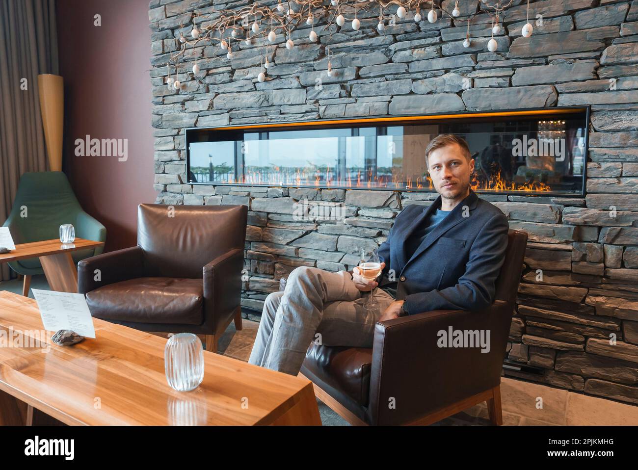 Man with wineglass sitting in chair at luxury hotel during vacation Stock Photo