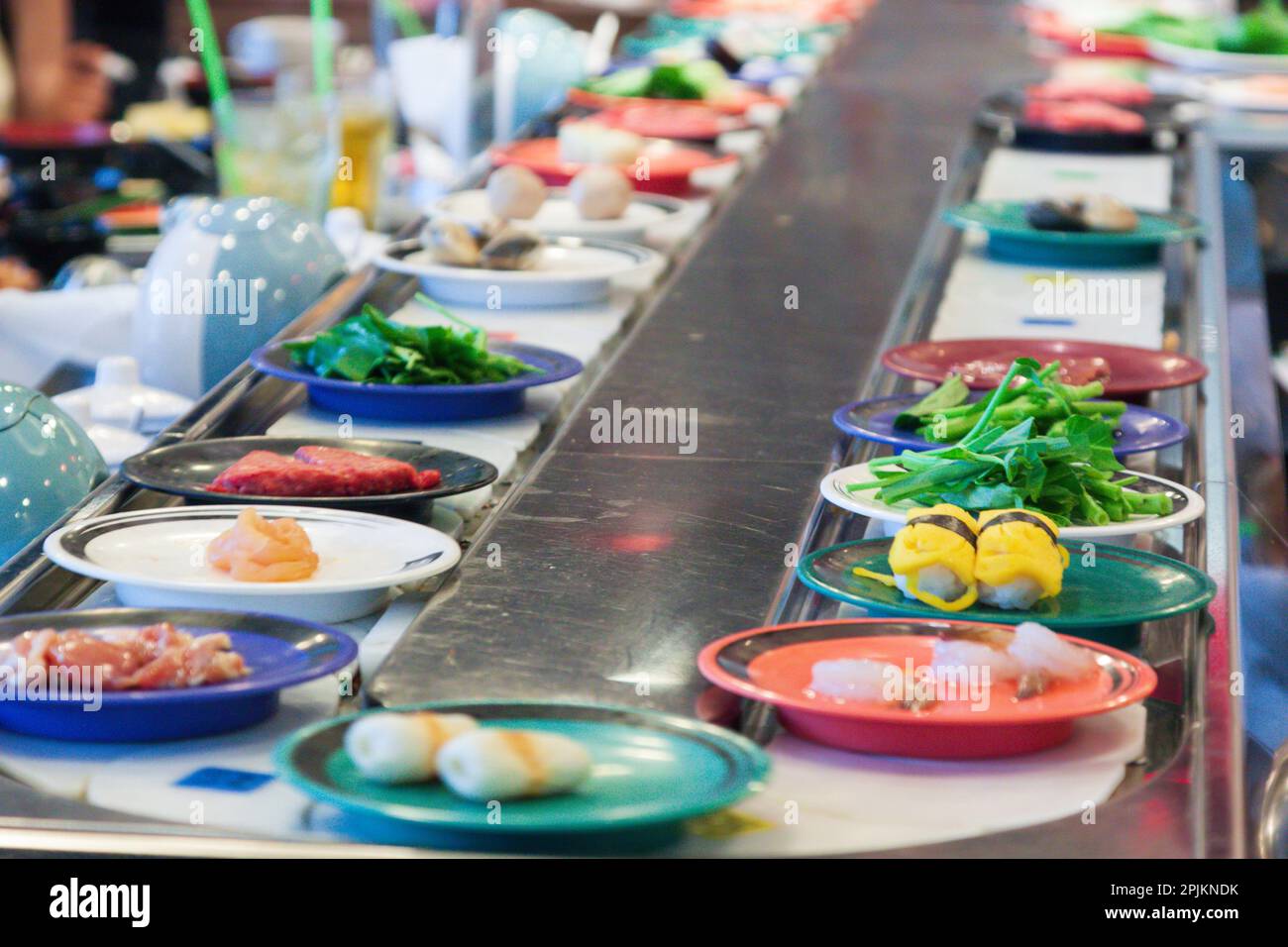 Thailand, Bangkok. Plates of sushi and other foods on a conveyor belt in a restaurant Stock