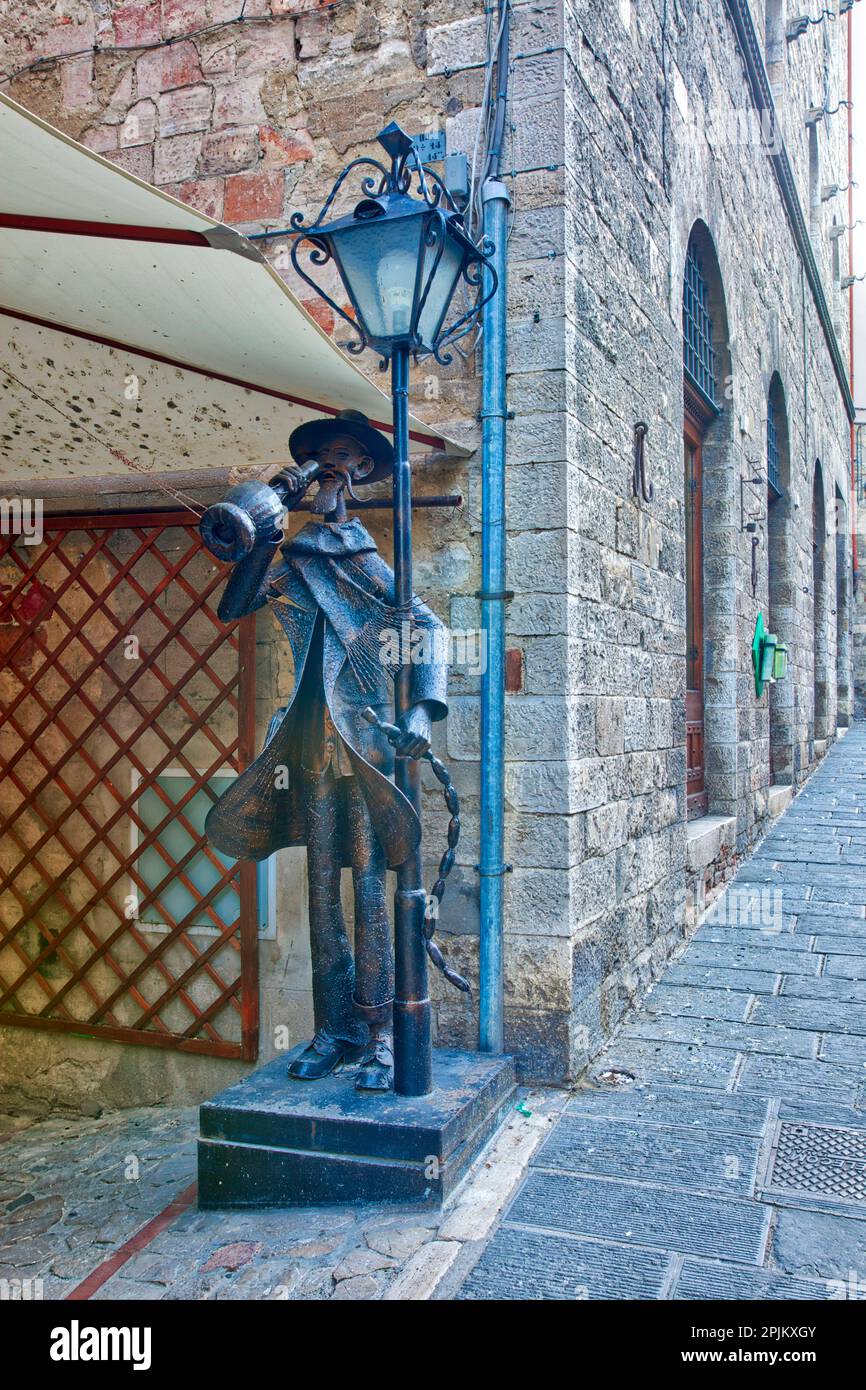 Italy, Umbria. Lamppost and statue of old man drinking wine in the historic town of Todi. (Editorial Use Only) Stock Photo
