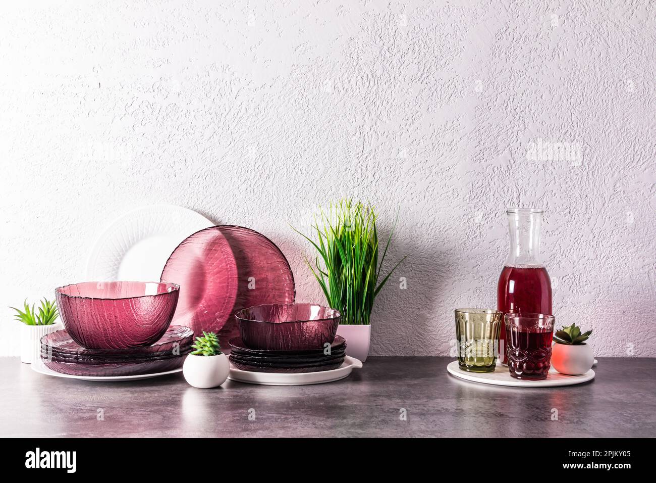 a set of modern glass burgundy dishes and a jug with grape juice on a
