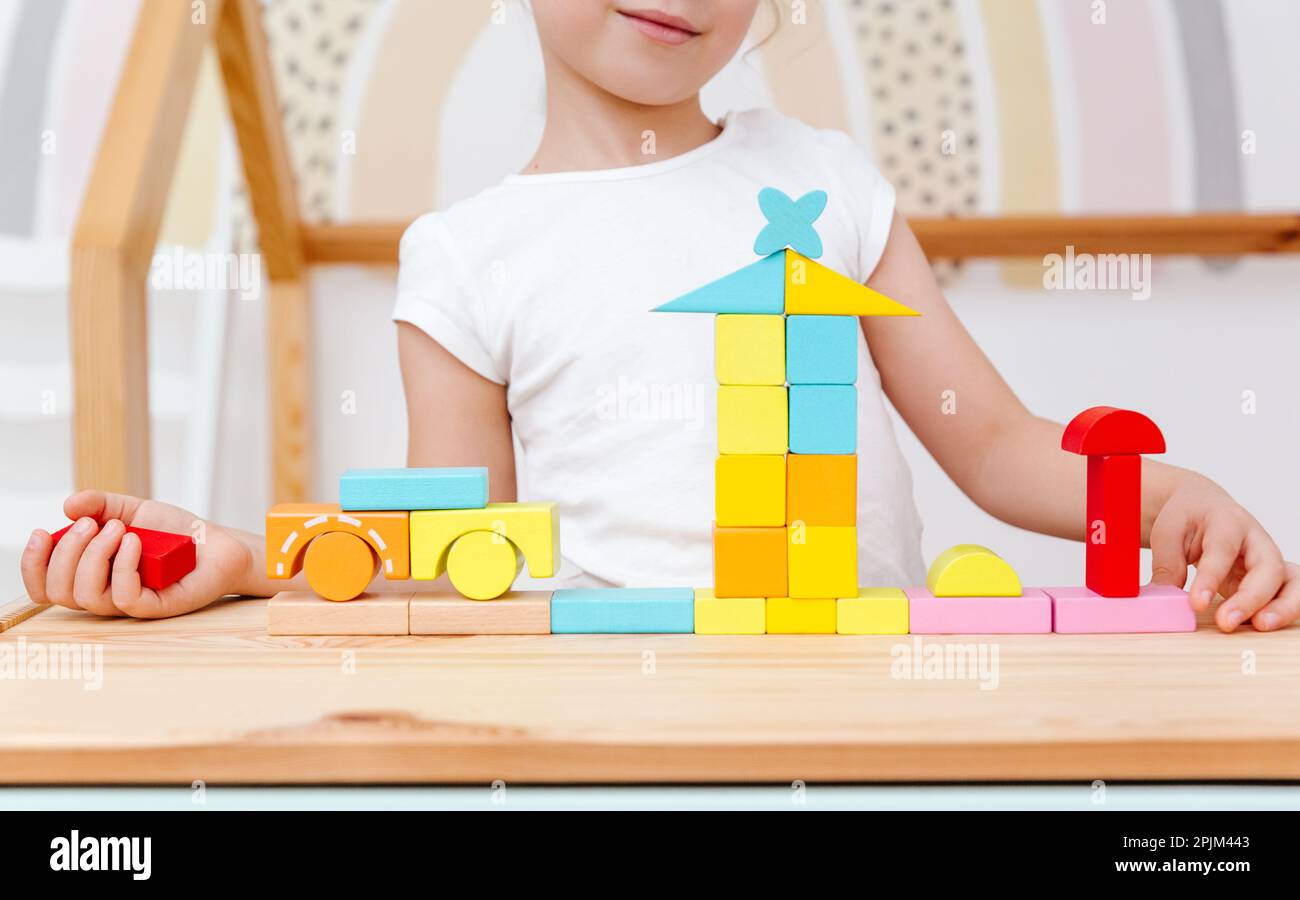 Little girl is playing with colorful wooden bricks. Wooden play set ...