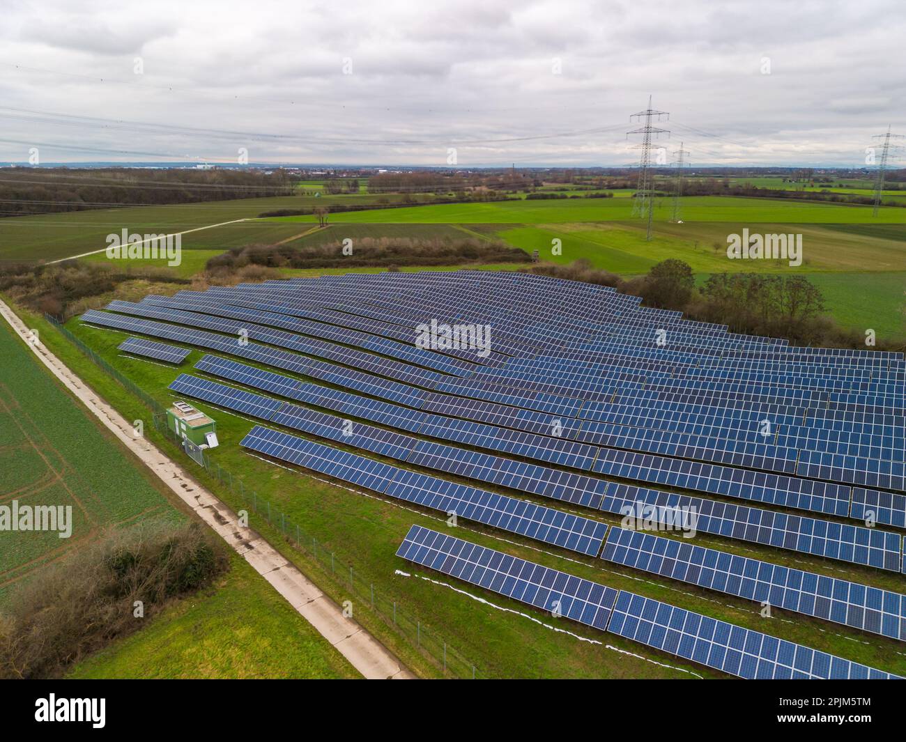 A solar park with PV panels on a farm track in the middle of meadows and fields in a rural region in Hesse, Germany Stock Photo