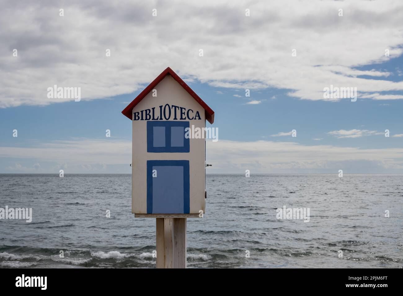 Little wooden house with title Biblioteca, built on the promenade of Atlantic ocean, to share the books. Blue sky with white clouds. Tarajalejo, Fuert Stock Photo