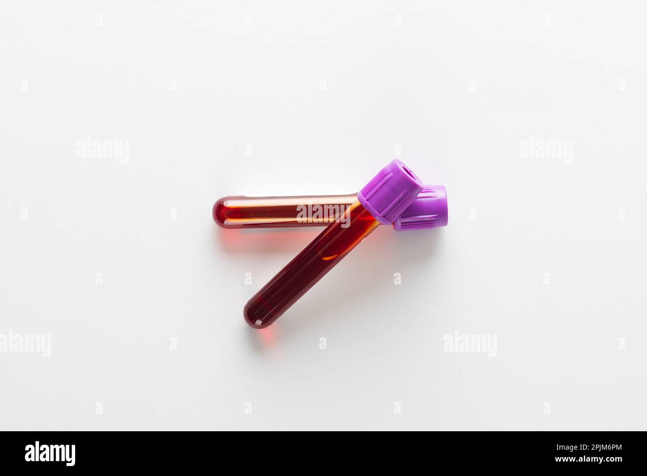 Two blood sample tubes with purple lids, on white background Stock