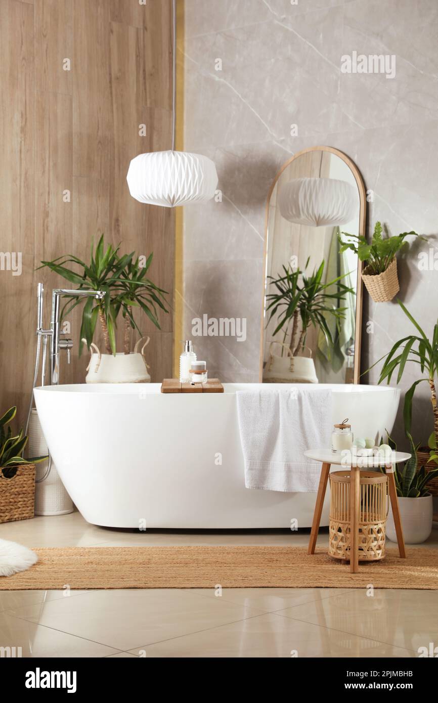 Modern white tub and beautiful green houseplants in bathroom. Interior ...