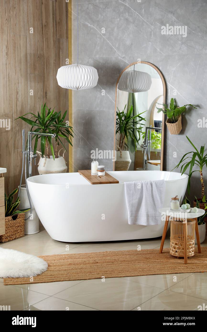Modern white tub and beautiful green houseplants in bathroom. Interior ...