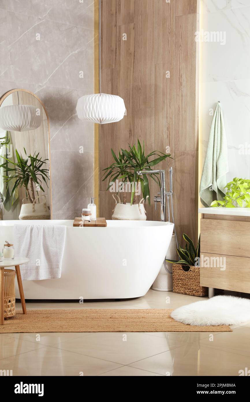 Modern white tub and beautiful green houseplants in bathroom. Interior ...