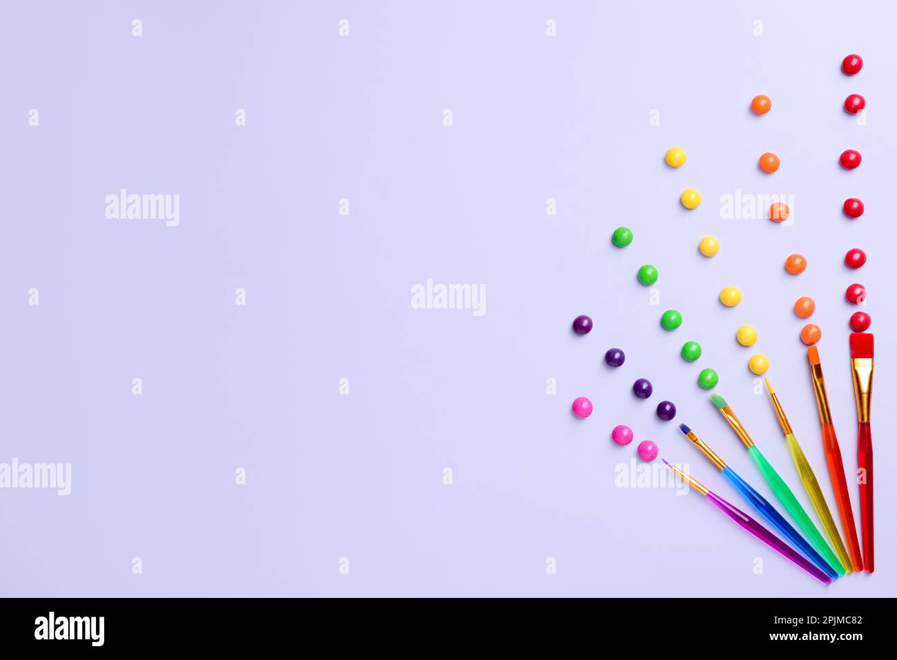Creative flat lay composition with paint brushes and colorful candies