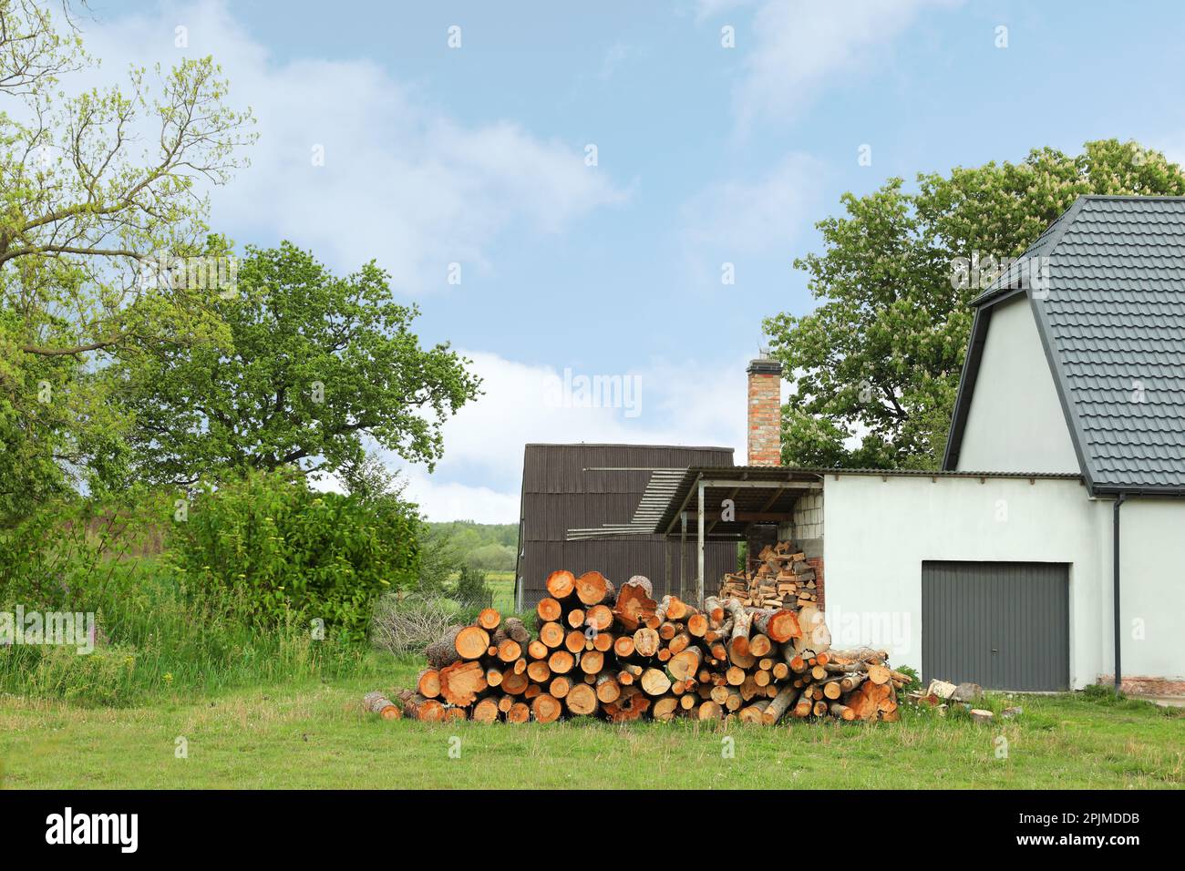 Pile of cut firewood near house on sunny day Stock Photo - Alamy