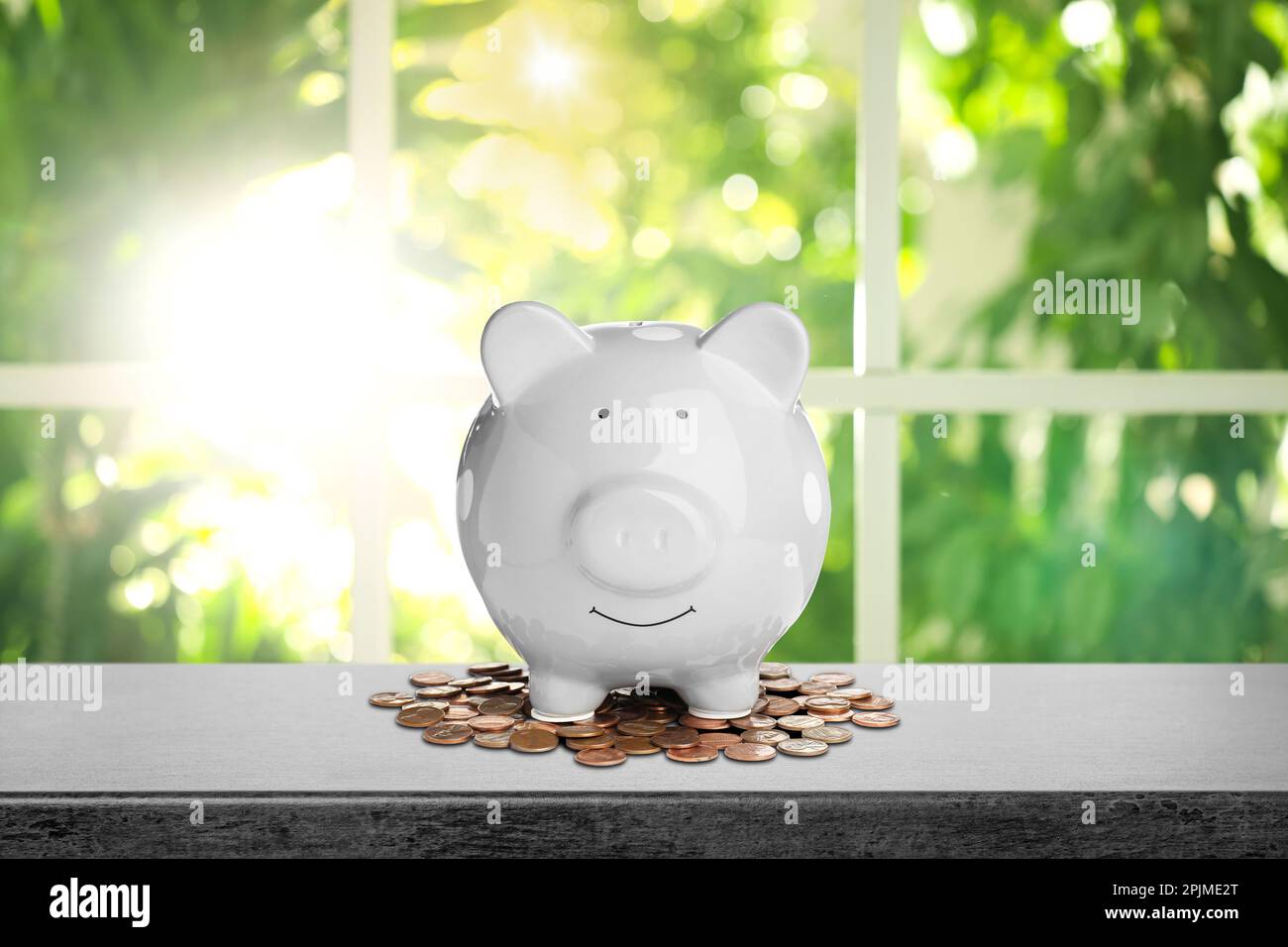 Piggy bank and coins on black stone table near window in room Stock ...