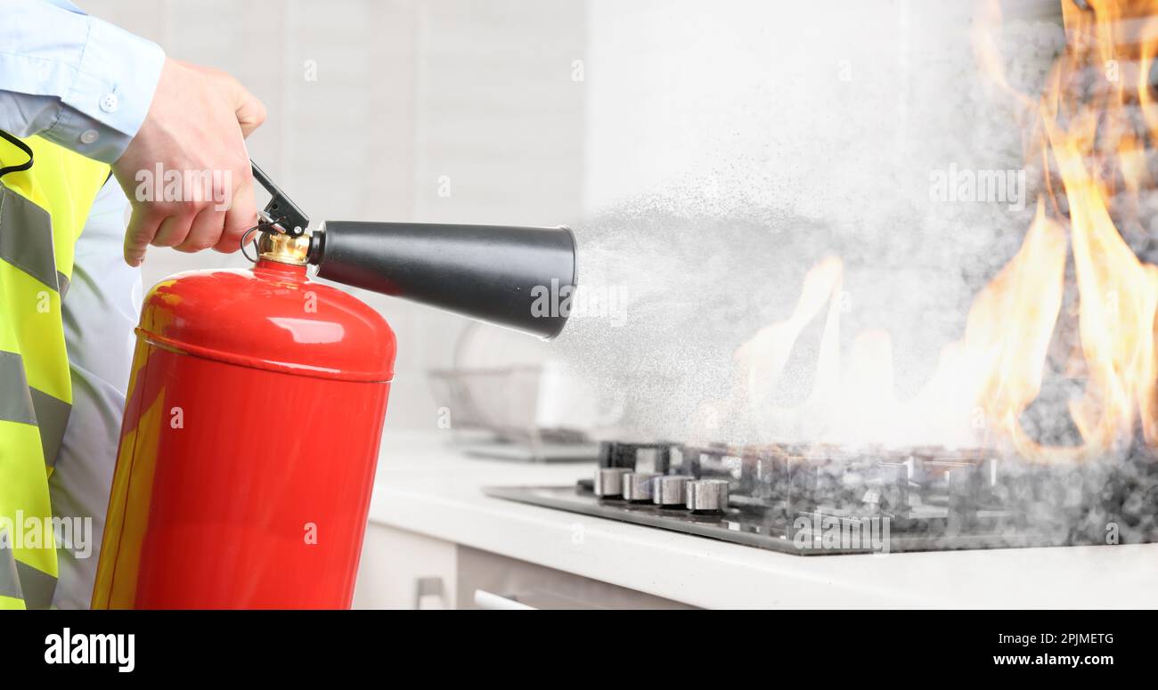 Man putting out burning cooktop with fire extinguisher in kitchen