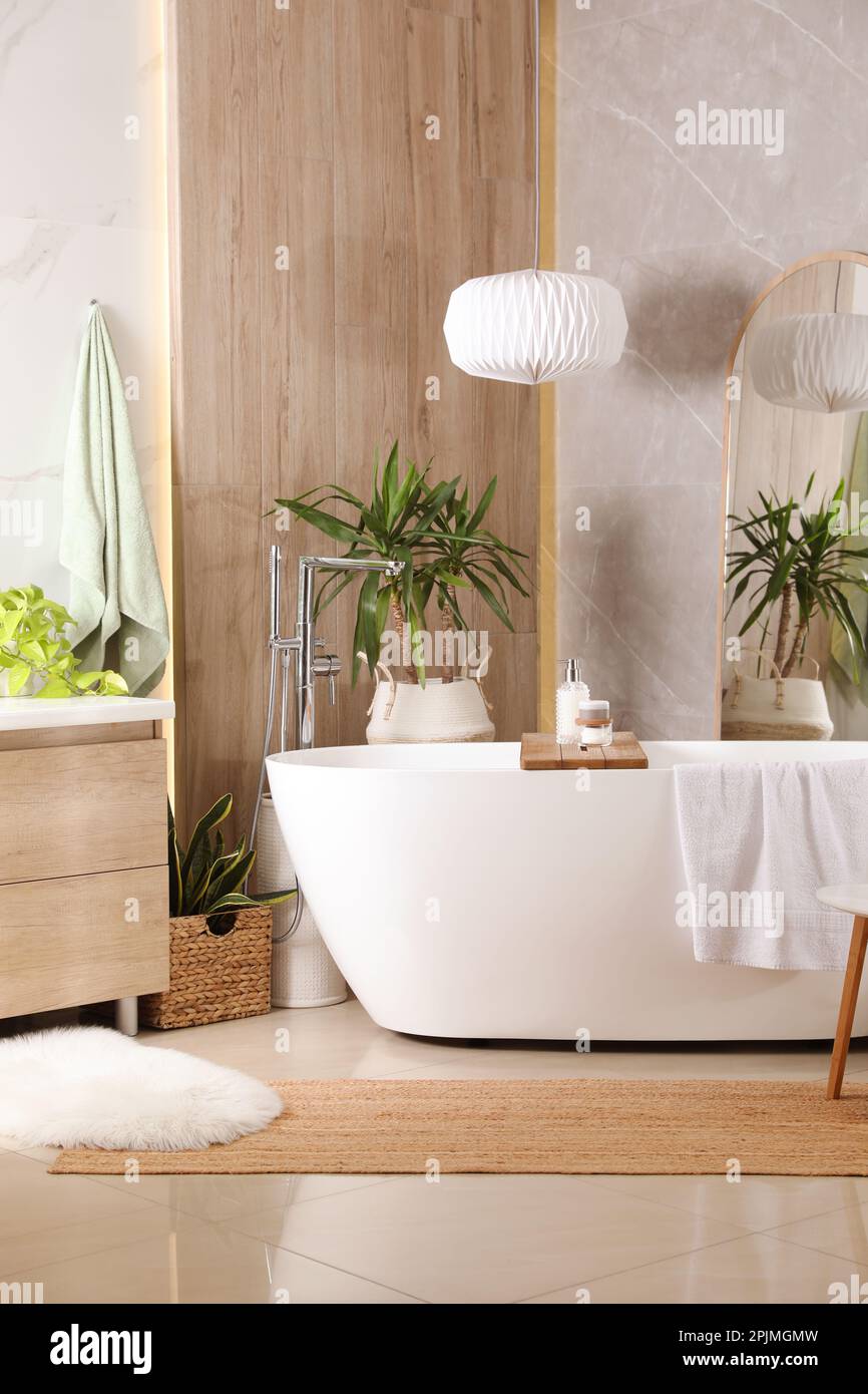 Modern white tub and beautiful green houseplants in bathroom. Interior ...