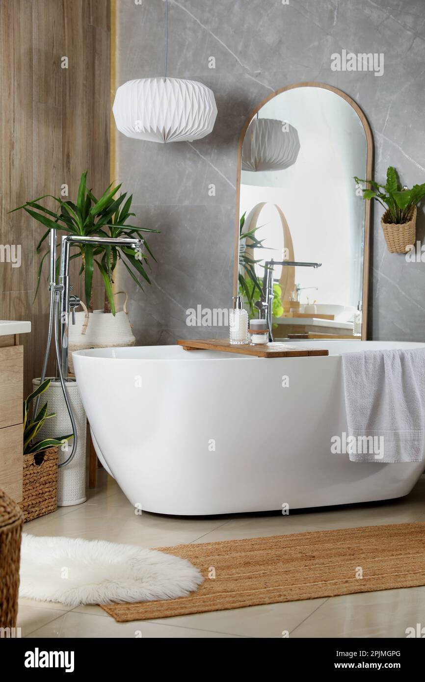 Modern white tub and beautiful green houseplants in bathroom. Interior ...