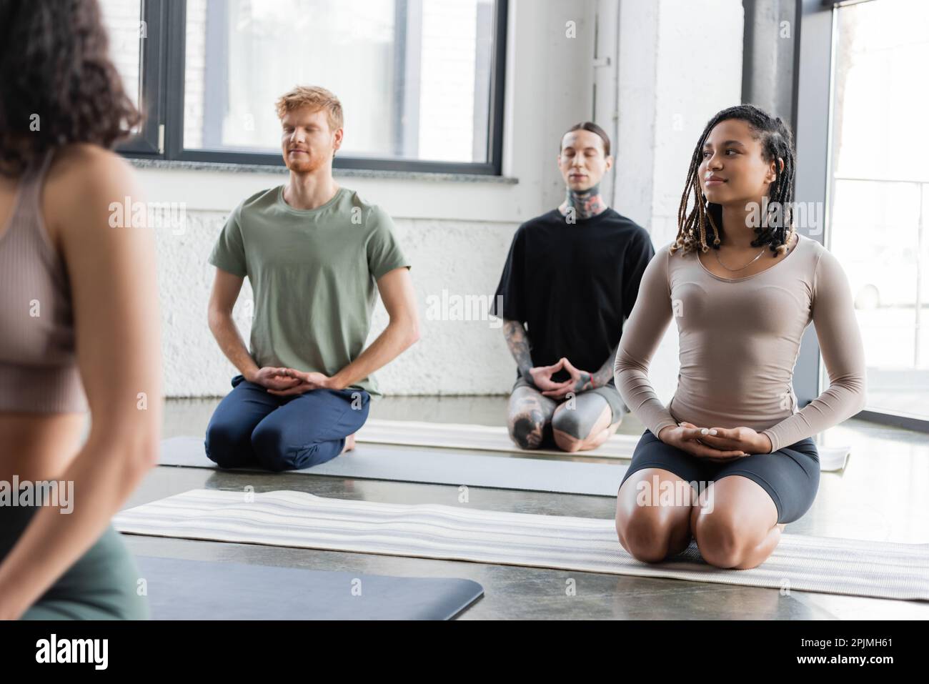 Group of women sitting on yoga mats at gym, doing breathing exercise and  meditating Stock Photo - Alamy