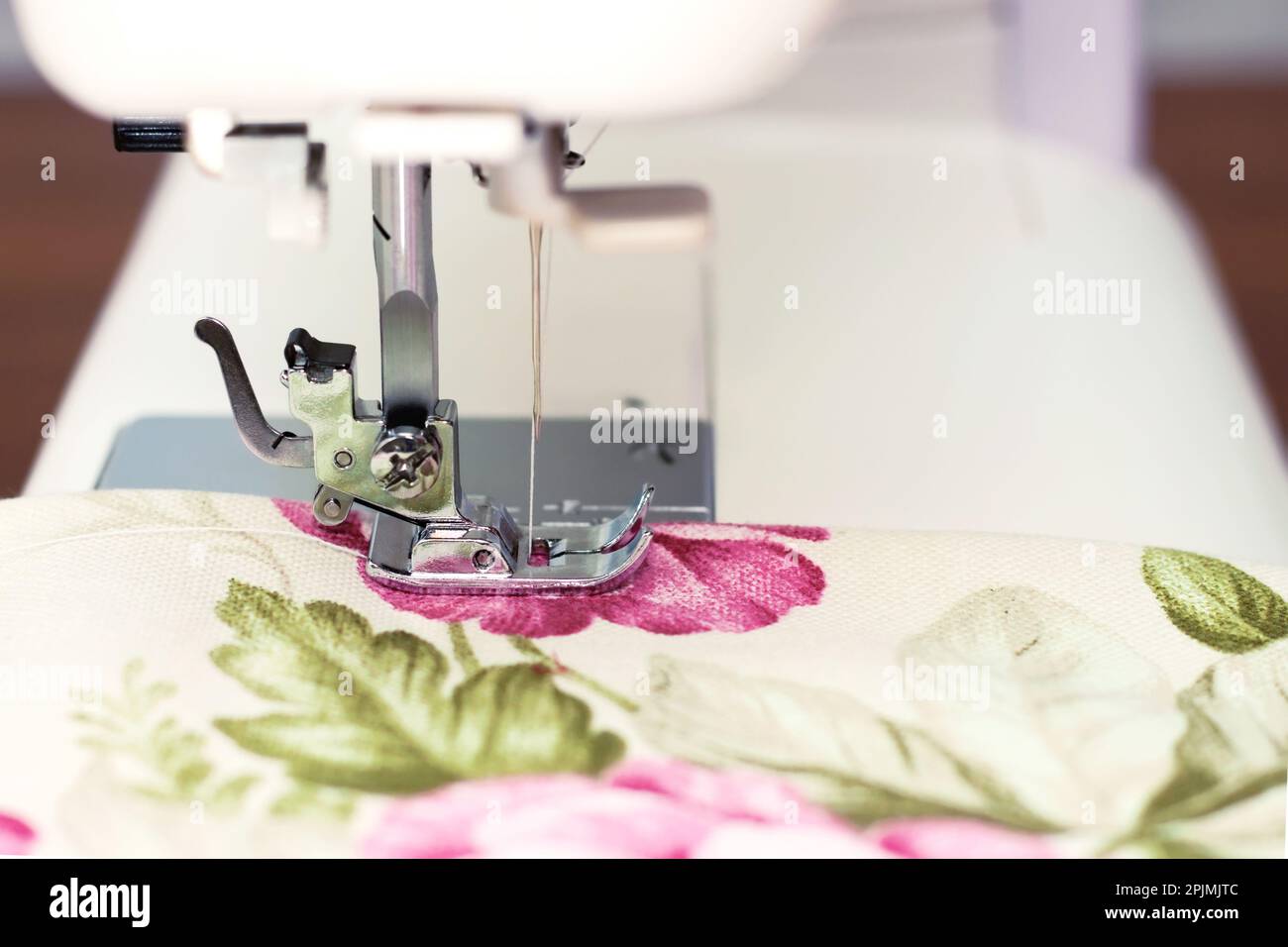 Modern sewing machine presser foot makes a seam on colofrul fabric