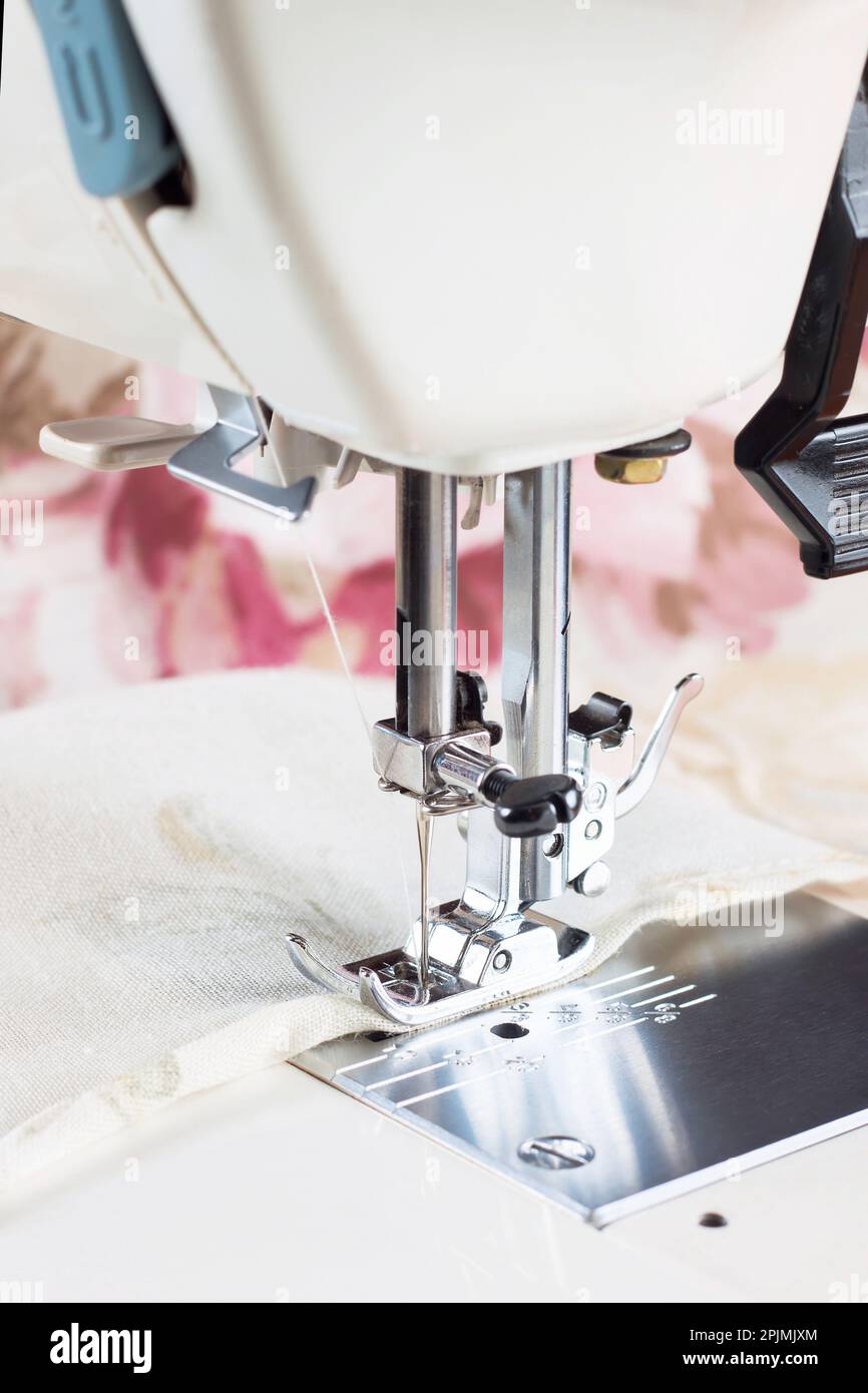 Modern sewing machine presser foot makes a seam on colofrul fabric