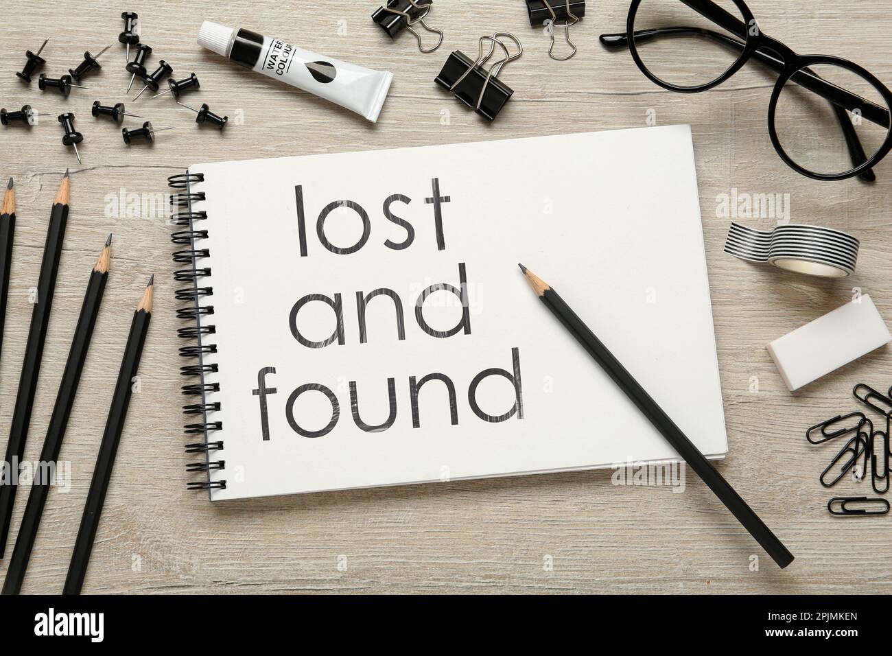 Flat lay composition of sketchbook with phrase Lost and Found on wooden