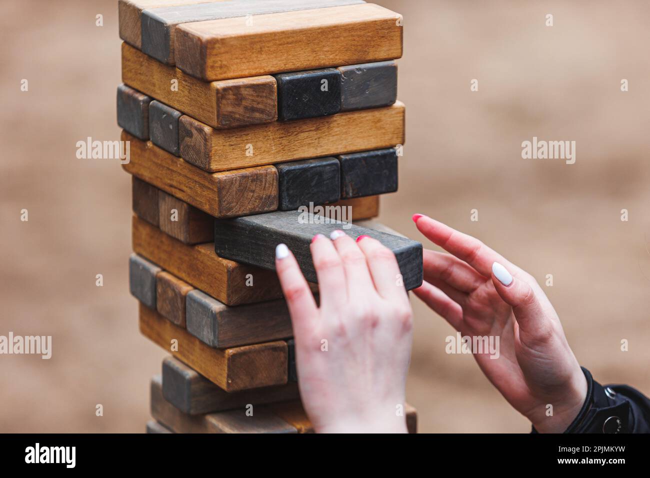 Jenga tower game in nature. Close-up shot of Jenga wooden block game. Concept of risk management. High quality photo Stock Photo