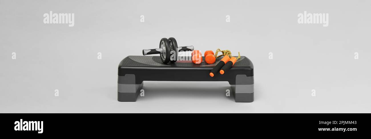 Step platform, skipping rope, dumbbells and abdominal wheel on light ...