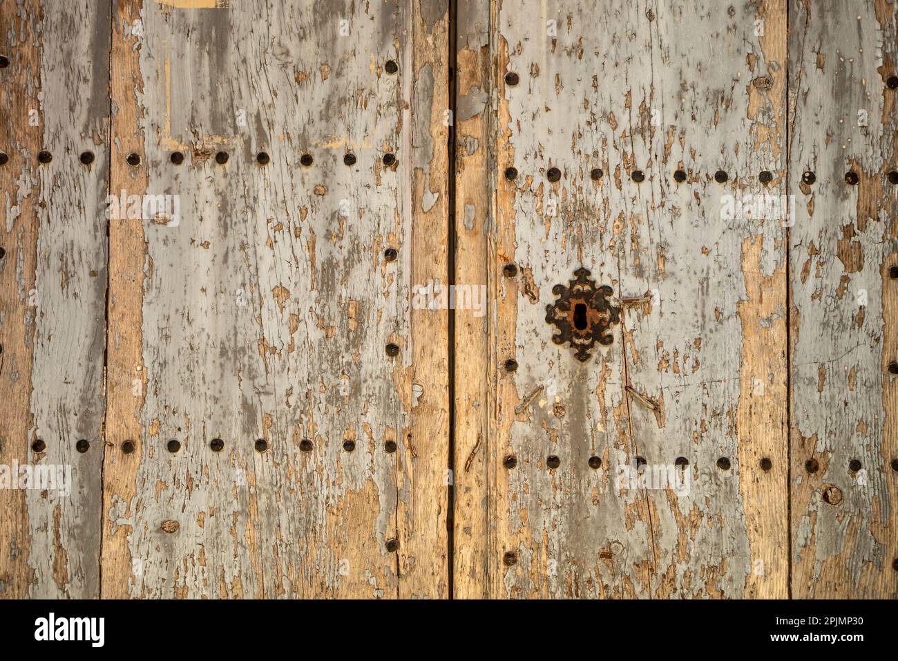 Old and time-worn solid wooden door with decorative metal elements Stock Photo