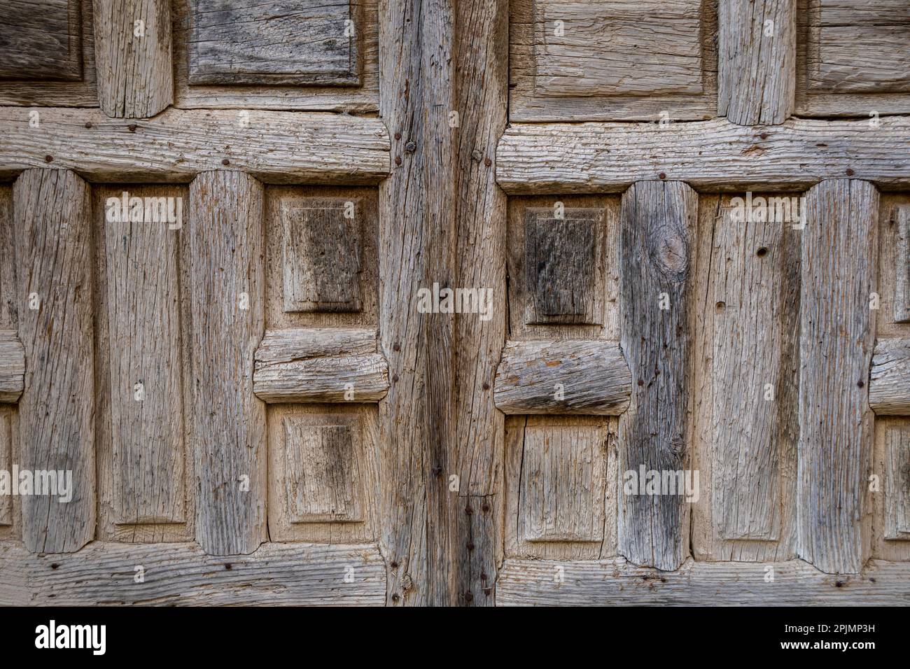 Old and time-worn solid wooden door with decorative metal elements Stock Photo