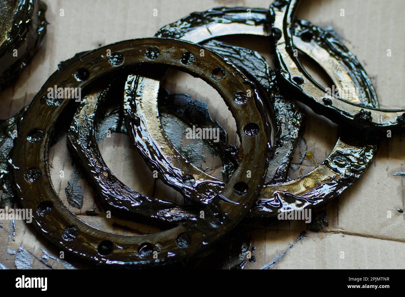 Car parts, rings and gaskets in lubricant lie on cardboard paper