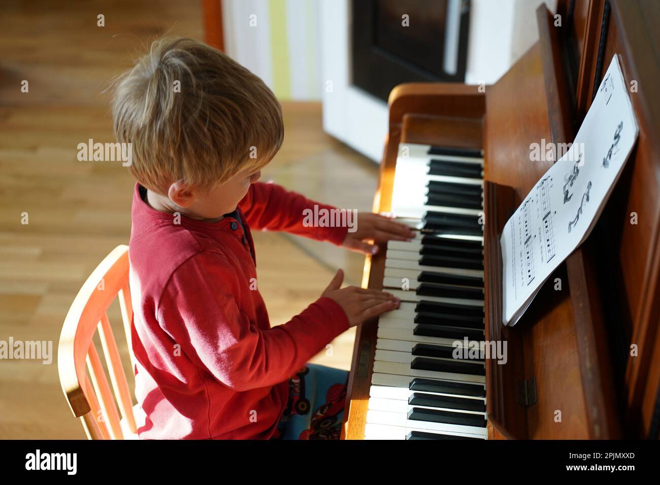 Adorable cute caucasian little toddler boy having playing piano at home. Education, child development concept. Selective focus Stock Photo