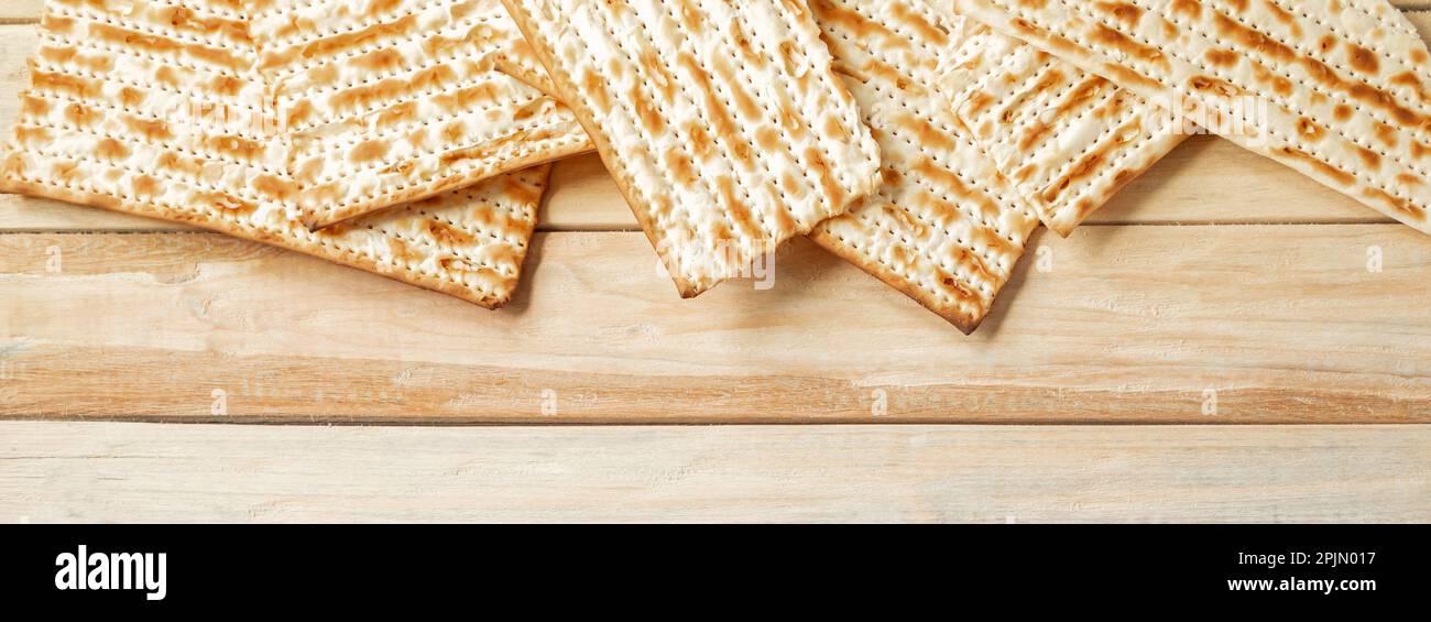 Background for the traditional Jewish holiday Pesach. Passover matzo bread on wooden table. Matzoh frame. Place for your text, banner format. Stock Photo