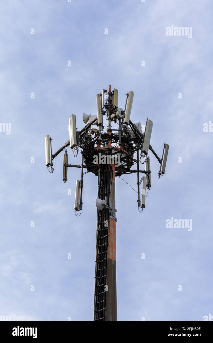 A close-up vertical view of a cellphone and internet 5G antenna with overcast sky copy space Stock Photo