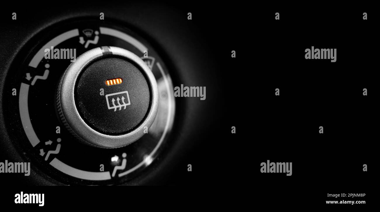 Defrost button in a car turned on with orange light glowing black