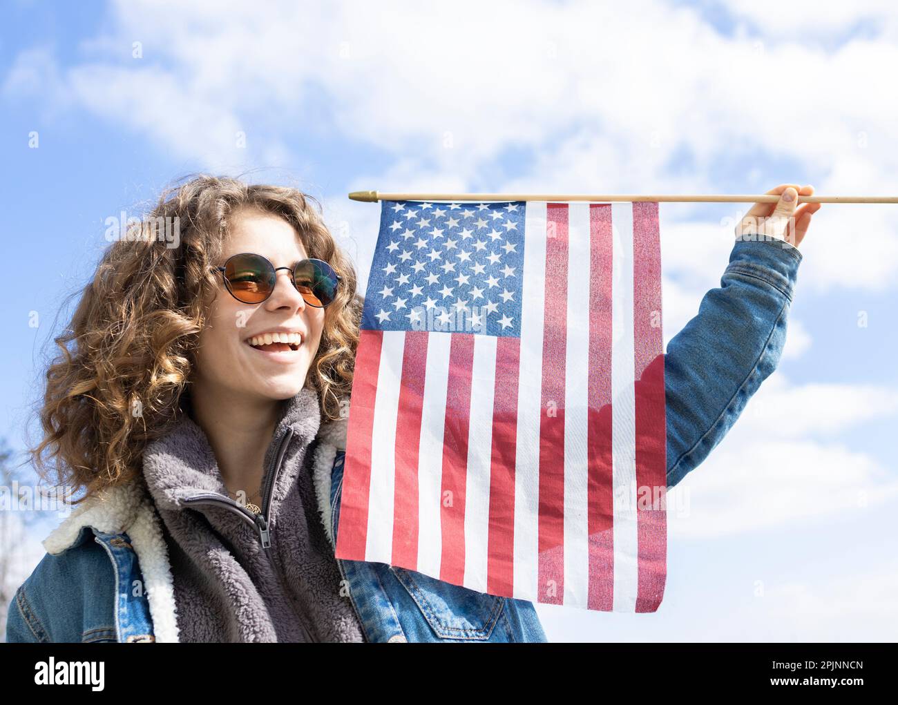 close-up portrait of a beautiful happy young woman in sunglasses with national american flag. july 4th celebration. Independence Day of the United Sta Stock Photo