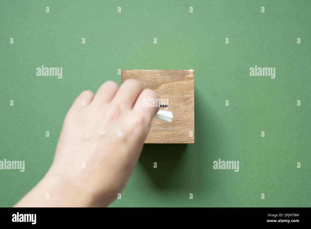Hand putting wooden ballot voting box on green background. top view Stock Photo