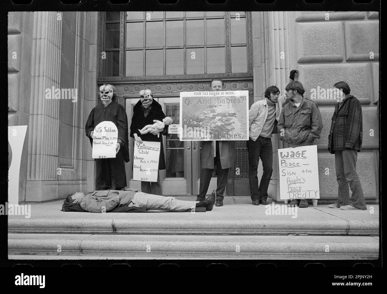 ANTI-WAR DEMONSTRATION AT I.R.S. with young Man lying on the ground and others wearing masks and carrying signs protesting the My Lai Massacre in Vietnam, Washington, DC, 4/28/1971. (Photo by Warren K Leffler/US News and World Report Collection) Stock Photo