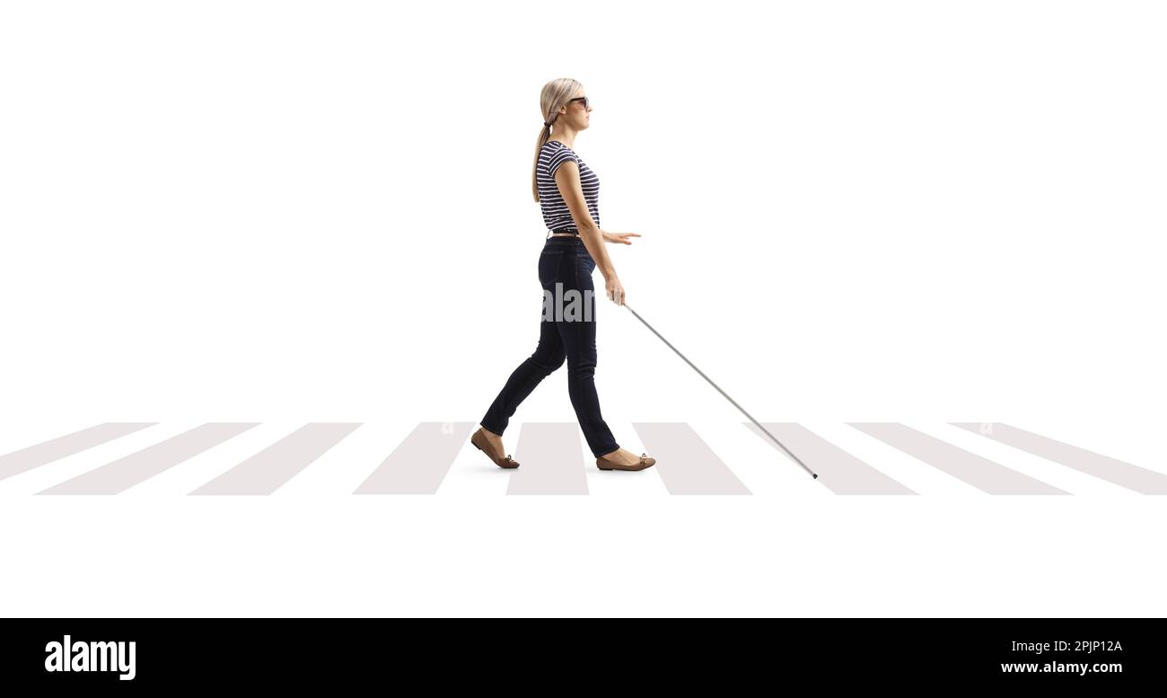 Full length profile shot of a young blind woman walking with a white cane at a pedestrian