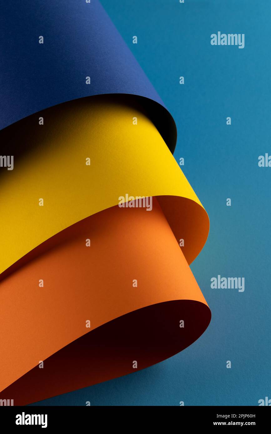 Close up of navy blue, yellow and orange paper on blue background Stock Photo