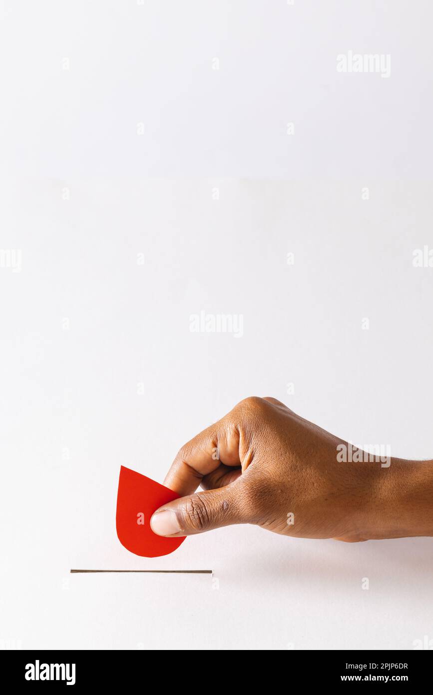 Hand of biracial man dropping blood drop into slot, on white background with copy space Stock Photo