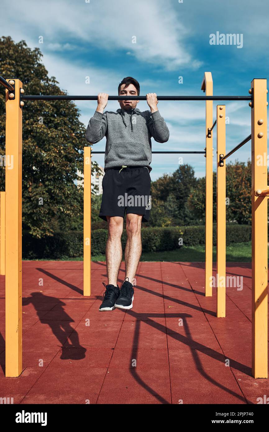 Young man doing pullups on pullup horizontal bar during his workout in a modern calisthenics