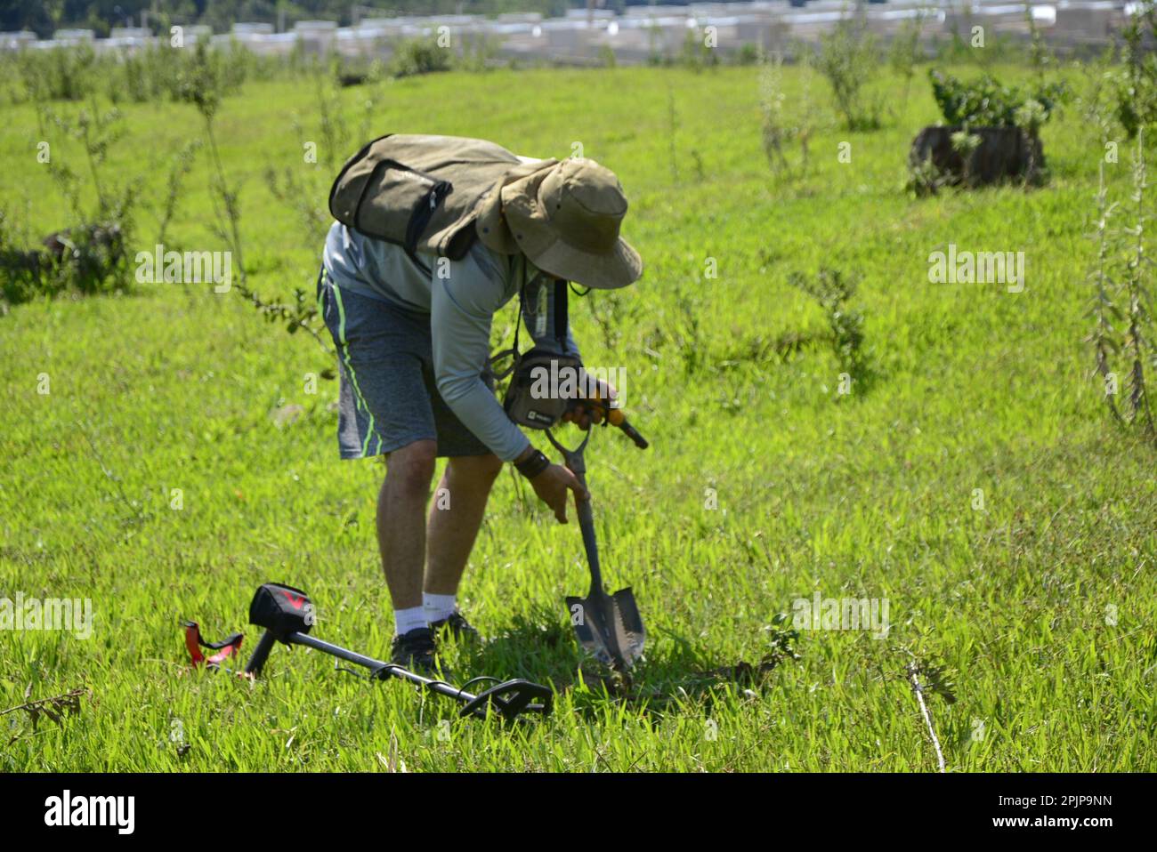 Man with detectorism equipment using shovel to dig find in treasure hunting competition. Intentional blurred background, selective focus Stock Photo