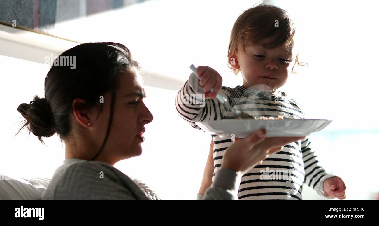 Funny baby toddler feeding mother reversing the roles. Adorable child ...