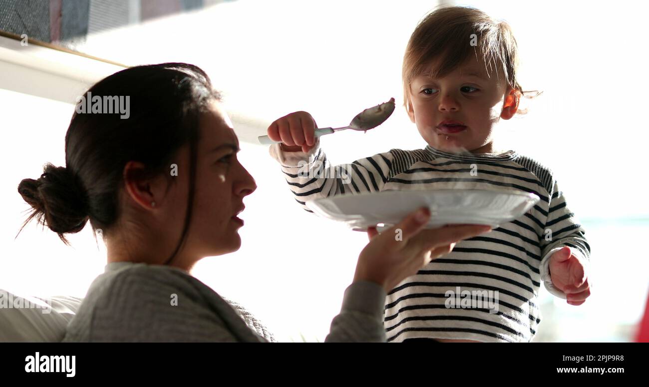 Funny baby toddler feeding mother reversing the roles. Adorable child ...
